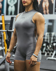 Woman wearing a gray sleeveless MNDST bodysuit in a gym setting
