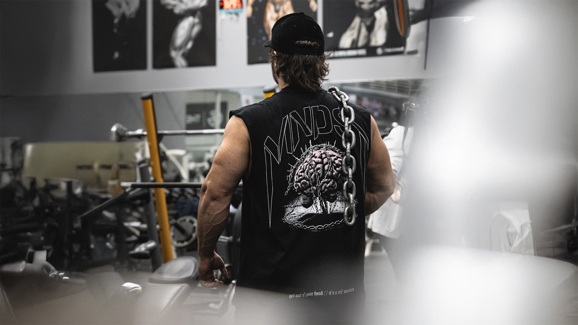 Person wearing a black tank top with graphic design in a gym setting