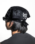 Person wearing a black bandana with white text on a white background