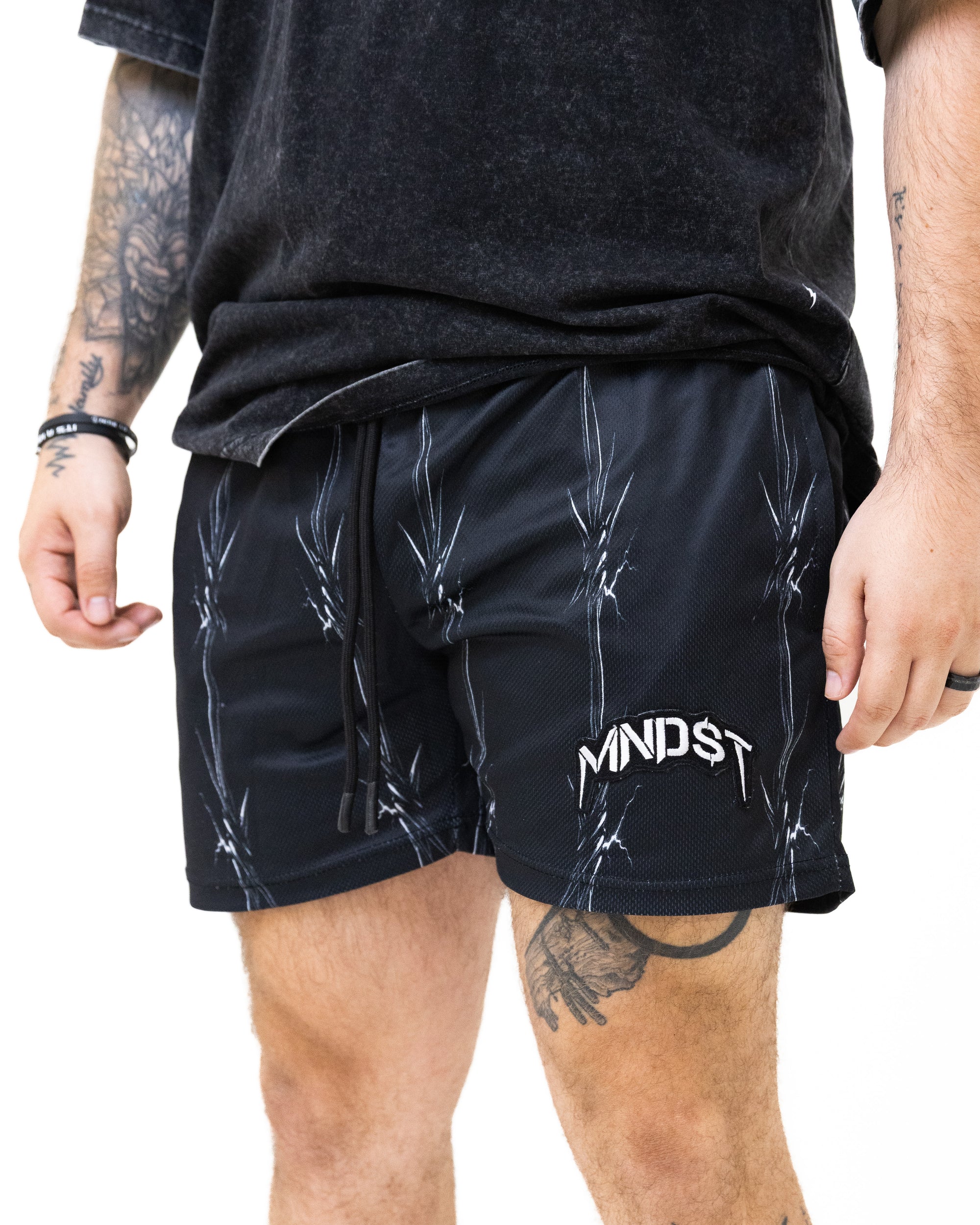 Person wearing black shorts with white text and a logo on a white background