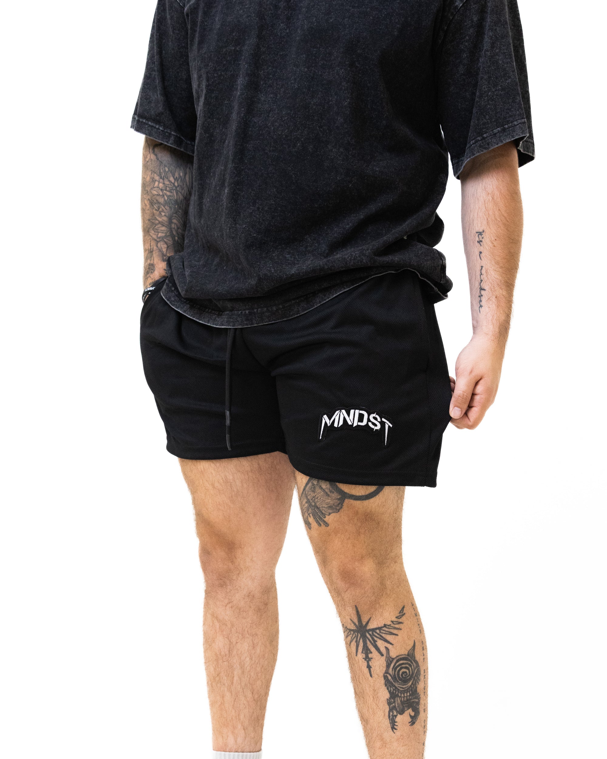 Person wearing black t-shirt and shorts with 'MINDST' logo on a white background