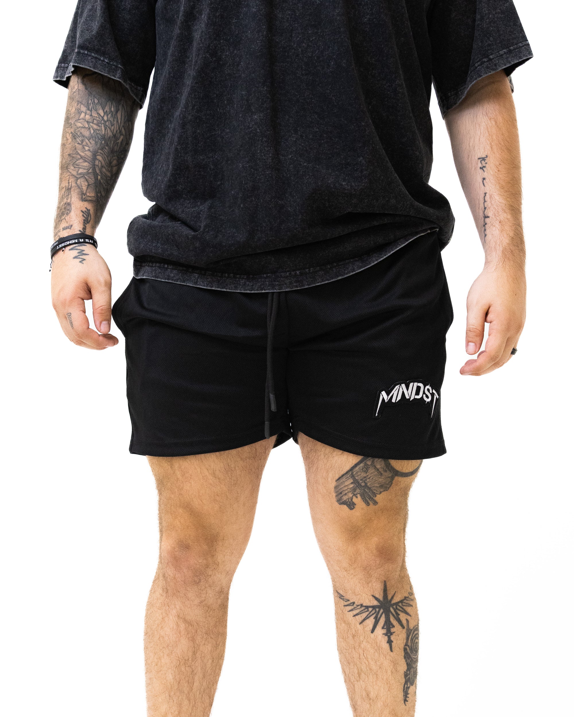 Person wearing black shorts with 'MINDS' logo on a white background