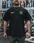 Man wearing a black t-shirt with text and graphics in a gym setting