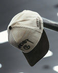 Man wearing a cream and brown corduroy MNDST TG Collab cap with text on a blurred background